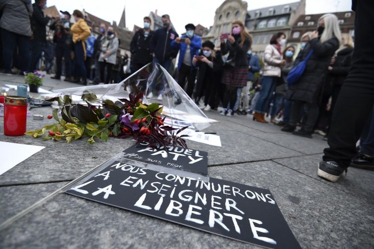 La gente se para cerca de flores y carteles que dicen "Continuaremos enseñando la libertad" mientras se reúnen en Estrasburgo, este de Francia, el 18 de octubre de 2020, en homenaje al profesor de historia Samuel Paty, dos días después de que un atacante que fue asesinado a tiros lo decapitó. por policías. Foto AFP.