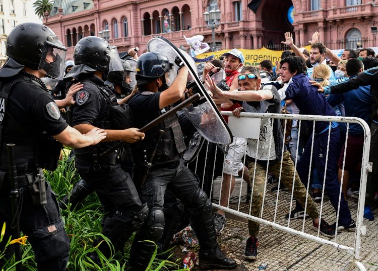 Los fanáticos se enfrentan a la policía antidisturbios mientras intentan llegar al palacio presidencial de la Casa Rosada para rendir homenaje a la leyenda del fútbol argentino Diego Maradona en Buenos Aires el 26 de noviembre de 2020. Sebastian Sanchi / AFP