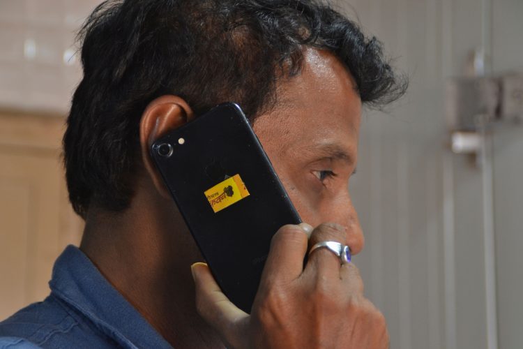 In this photo illustration taken on October 13, 2020 a man uses a mobile phone with a "chip" manufactured by Shreeji Gaushala placed on the phone cover, which they claim can protect people from cellphone radiation, in Rajkot some 220 Km from Ahmedabad. - An Indian government unit established to develop soaps and medicinal products from cow dung has branched out with a "chip" it claims can protect people from cellphone radiation. Without explaining how the technology works, the head of the National Cow Commission -- set up last year -- said the device could simply be placed inside a mobile phone's protective cover. (Photo by - / AFP)