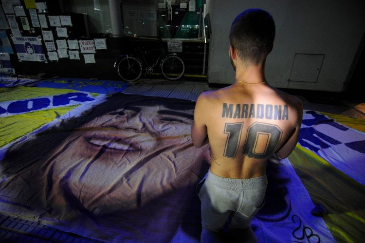 Un partidario del ex futbolista argentino y entrenador de Gimnasia y Esgrima La Plata, Diego Maradona, se arrodilla frente a la clínica privada donde fue sometido a una cirugía cerebral por un coágulo de sangre, en Olivos, provincia de Buenos Aires, Argentina. JAVIER GONZALEZ TOLEDO / AFP