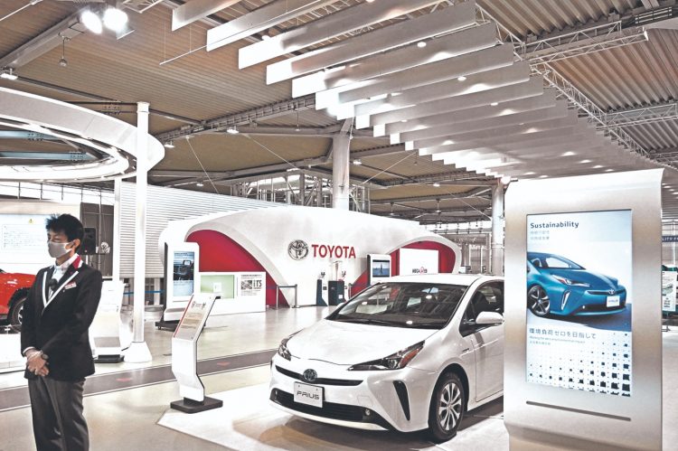 (FILES) In this file photo taken on November 6, 2020, a staff member stands in a Toyota showroom in Tokyo. - Japan's Toyota reclaimed the title of world's top-selling automaker in 2020, according to data released by the firm on January 28, 2021, pushing Volkswagen into second place for the first time in five years. (Photo by Philip FONG / AFP)