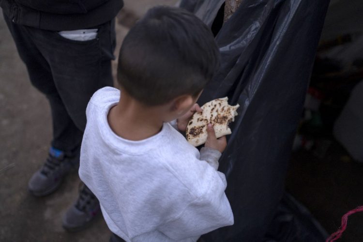 Un niño de 4 años del estado de Michoacán come una quesadilla luego de que su familia fuera devuelta a México el 13 de diciembre de 2019 en Ciudad Juárez. FOTO / AFP (archivo)