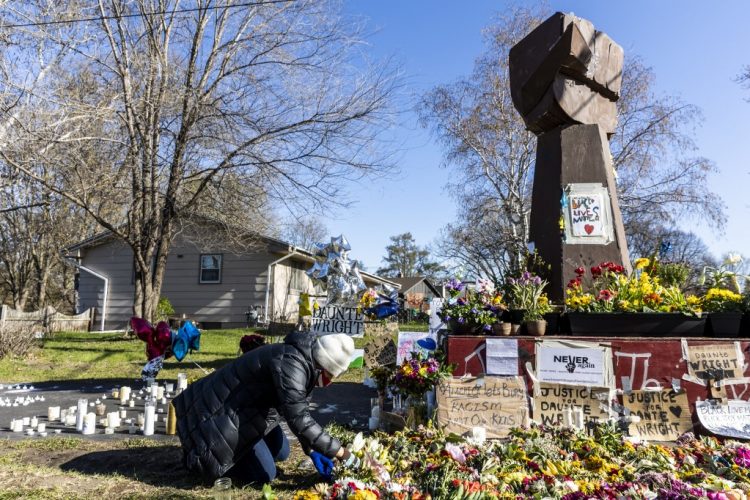 Uno de los cuidadores del memorial de Daunte Wright arregla las flores en Brooklyn Center, Minnesota, el 20 de abril de 2021. FOTO / AFP