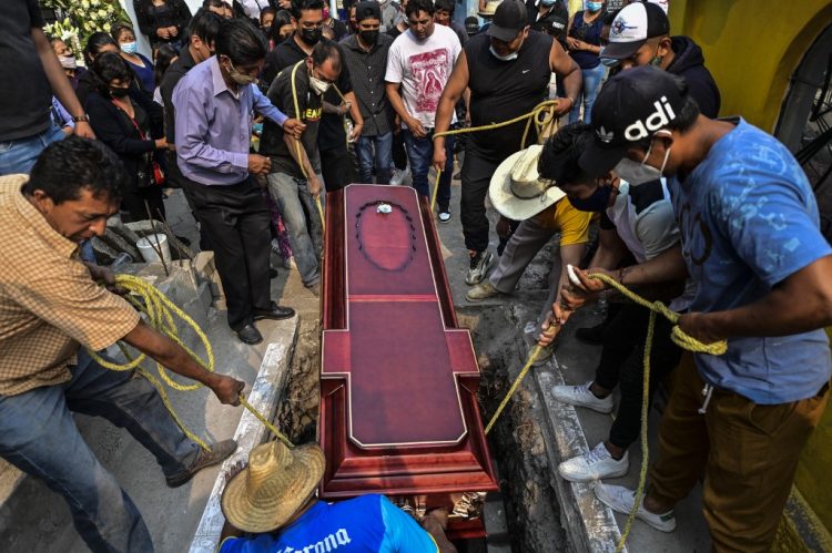 Familiares entierran el ataúd con los restos de Juan Luis Díaz Galicia durante su funeral en la Ciudad de México el 5 de mayo de 2021. - Juan Luis Díaz murió en un accidente de tren luego de que colapsara una línea elevada del metro en la capital de México. FOTO / AFP