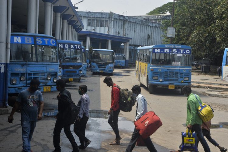 Los pasajeros caminan en la estación de la Corporación de Transporte del Estado de Bengala del Norte (NBSTC) en Siliguri el 6 de mayo de 2021 luego del anuncio del departamento de estado de Bengala Occidental de servicios de autobús limitados en medio de la pandemia del coronavirus Covid-19. FOTO / AFP