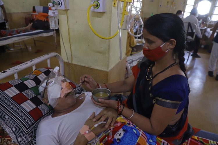 Se ve a un asistente junto a un paciente que se recuperó del coronavirus Covid-19 y ahora está infectado con Black Fungus, una infección fúngica mortal en el Netaji Subhash Chandra Bose Medical College en Jabalpur el 21 de mayo de 2021. FOTO / AFP