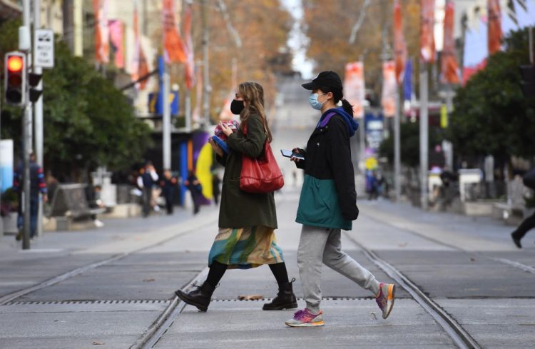 Las personas con máscaras cruzan una calle comercial casi vacía en Melbourne el 26 de mayo de 2021, mientras la segunda ciudad más grande de Australia lucha por contener un brote creciente de Covid-19. FOTO / AFP