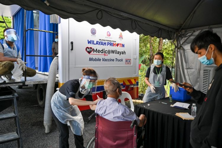 Un miembro del personal médico administra una dosis de la vacuna contra el coronavirus Sinovac Covid-19 a un anciano fuera de un camión móvil de vacunas en Kuala Lumpur el 21 de junio de 2021. FOTO / AFP