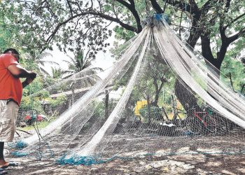 Reparan sus redes mientras el oleaje es fuerte en La Unión