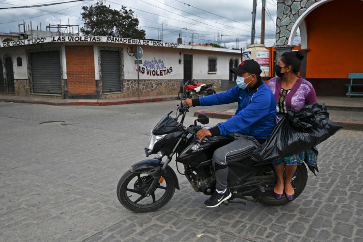 Una pareja conduce una motocicleta en una calle vacía por limitantes ante la pandemia. Foto AFP.