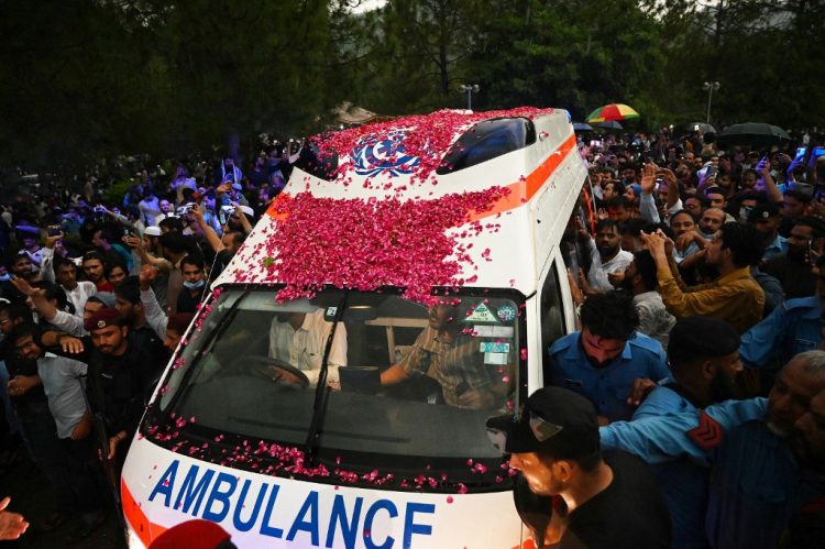 Simpatizantes y funcionarios se reúnen alrededor de una ambulancia que transporta el ataúd del científico nuclear de Pakistán Abdul Qadeer Khan para su funeral frente a la mezquita de Faisal tras su muerte en Islamabad el 10 de octubre de 2021. FOTO / AFP