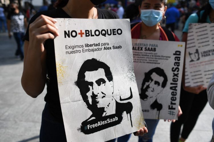 La gente sostiene carteles con la imagen del empresario colombiano Alex Saab, quien se encontraba distanciado a Estados Unidos, durante una manifestación exigiendo su liberación, en la plaza Bolívar de Caracas, el 17 de octubre de 2021. FOTO / AFP