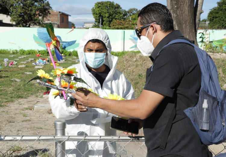 Área COVID-19. José Roberto Tomasín entrega unas flores a un encargado del cementerio La Bermeja para que las coloque en el sepulcro de su madre, quien falleció el año pasado debido al coronavirus./Foto DES: Edison González.