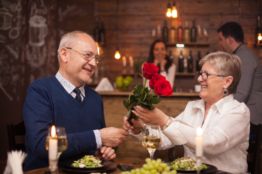 cheerful senior couple happy about their date husband giving flower to his wife enjoying retirement