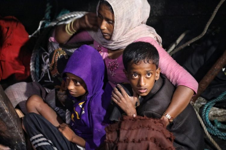 Refugiados rohingyas se sientan en un bote de madera mientras un funcionario indonesio realiza una evacuación en el puerto de Krueng Geukueh en Lhokseumawe, provincia de Aceh, luego de que fueran rescatados por la armada de Indonesia en las aguas de Bireuen. Foto AFP.