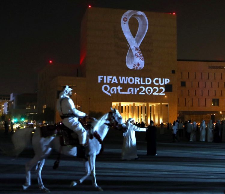 (FILES) In this file photo taken on September 3, 2019, a mounted policeman rides past a building on which the official logo of the FIFA World Cup Qatar 2022 logo is projected at the Qatari capital Doha's traditional Souq Waqif market. - Migrant labourers are working through the night near the World Cup clock that will start counting down 200 days to kick-off on May 5, 2022, with hosts Qatar facing mounting questions over costs and conditions for fans. (Photo by AFP)
