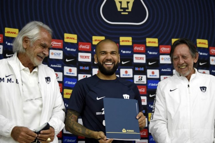 La estrella del fútbol internacional brasileño Dani Alves (C) sonríe flanqueado por el presidente de los Pumas de México, Leopoldo Silva (R) y el director deportivo Miguel Mejía (L) después de firmar su contrato para el actual torneo Apertura-2022, en las instalaciones del equipo en la Universidad Nacional Autónoma de México, en la Ciudad de México. (Photo by ALFREDO ESTRELLA / AFP)