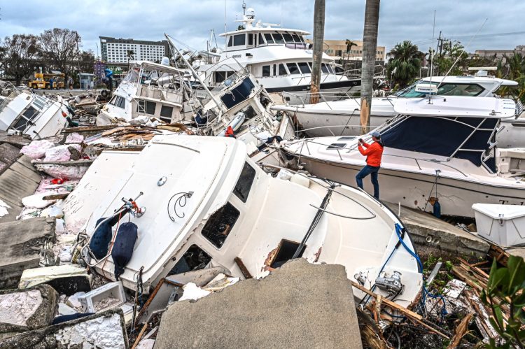 Un hombre toma fotos de los barcos dañados por el huracán Ian en Fort Myers, Florida tras el paso de Ian.  Foto AFP.