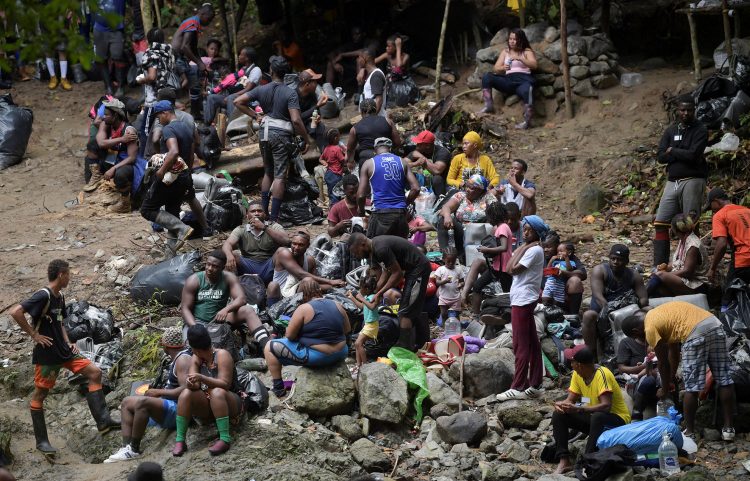 Haitian migrants rest as they cross the jungle of the Darien Gap, near Acandi, Choco department, Colombia, heading to Panama, on September 26, 2021, on their way trying to reach the US. - From Acandi, they started on foot -- and armed with machetes, lanterns and tents -- the dangerous trek of at least five days to Panama through the Darien jungle, battling snakes, steep ravines, swollen rivers, tropical downpours and criminals often linked to drug trafficking. (Photo by Raul ARBOLEDA / AFP)