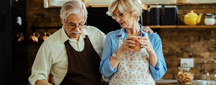 Senior woman and her husband enjoying in cooking in their kitchen.
