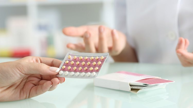 Close up of a girl hands buying contraceptive pills and pharmacist explaining in a pharmacy