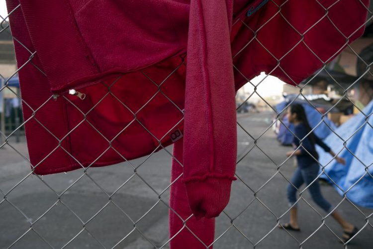 Una niña corre cerca de ropa tendida para secarse en la cerca de un campamento improvisado de solicitantes de asilo y refugiados en el cruce fronterizo de El Chaparral en Tijuana, estado de Baja California. Foto AFP referencia.