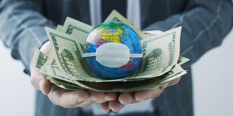 businessman holding a world globe with a protective mask on top of a handful of dollar bills, depicting the economic consequences of the coronavirus pandemic or of the pollution and climate change