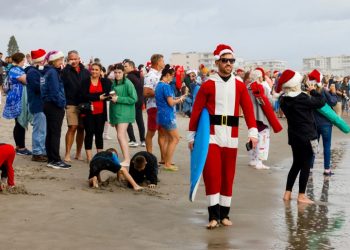 Papás Noel surfistas toman una playa de Florida por diversión y una buena causa
