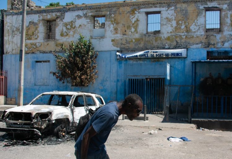 Un hombre sale de la zona penitenciaria y agacha la cabeza debido a los disparos cercanos, en Puerto Príncipe, Haití. Foto AFP.