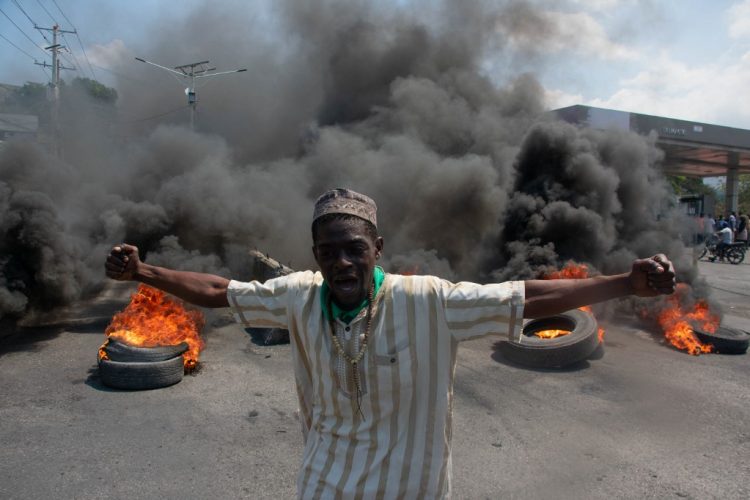 Un manifestante reacciona mientras se queman neumáticos en la calle durante una manifestación tras la dimisión de su primer ministro Ariel Henry, en Puerto Príncipe.