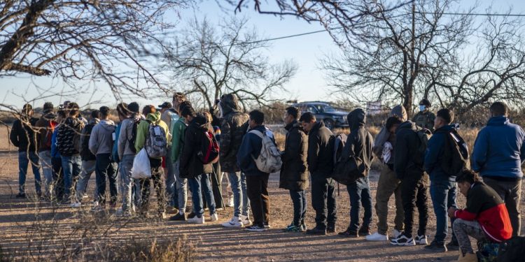 A group of migrants are processed by Border Patrol after crossing the river illegally near the highway on February 4, 2024 outside Eagle Pass, Texas. Eagle Pass, about 20 miles (30 kilometers) from Quemado, has become the epicenter of a prickly conflict between Texas Governor Greg Abbott, a Republican, and the Biden administration. The federal government is suing Abbott for taking control of Shelby Park that includes an access ramp to the river, and for laying barbed wire along the riverbank. (Photo by SERGIO FLORES / AFP)