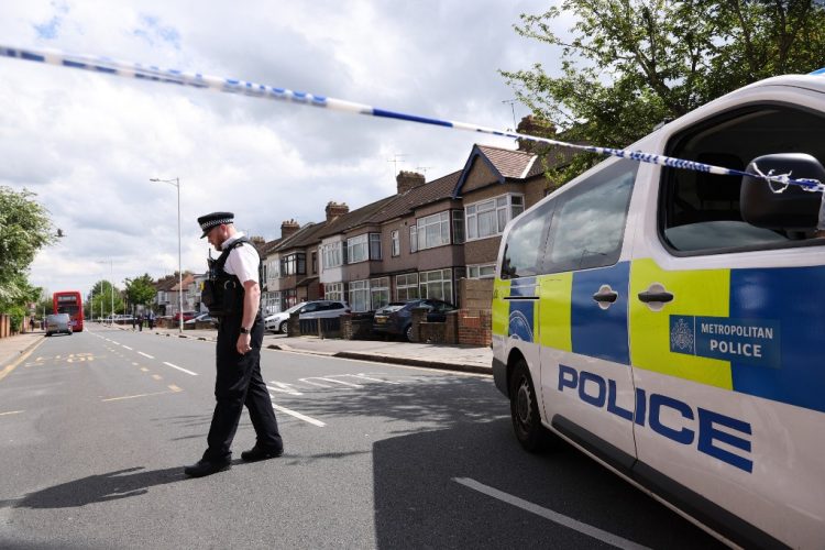 Un oficial de policía está de servicio en un cordón de la escena del crimen en Hainault. Foto AFP.