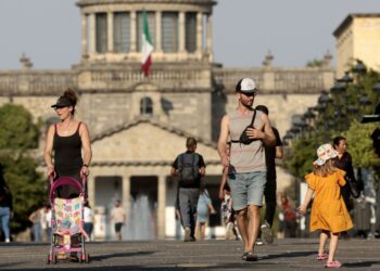 People walk in the the sun during a heat wave hitting the country, in Guadalajara, Jalisco state, Mexico, on May 9, 2024. More than a dozen states in Mexico reached a record maximum of 45°C. (Photo by ULISES RUIZ / AFP)