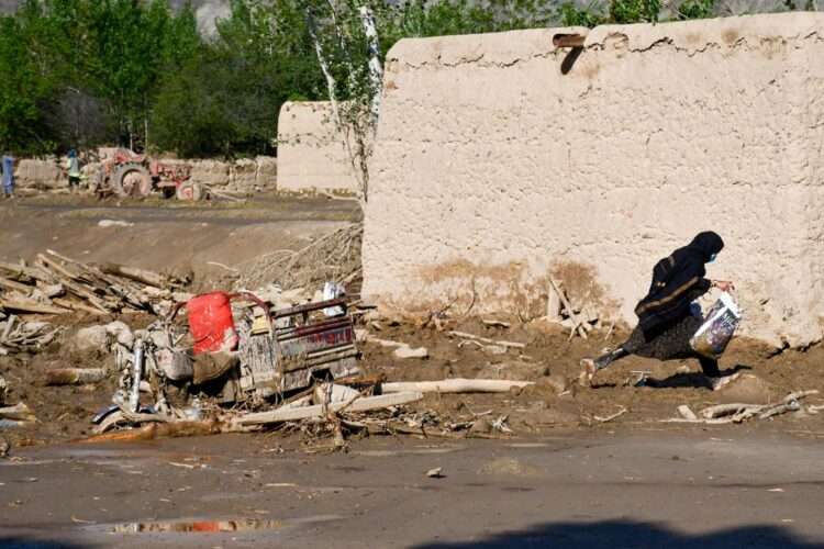 A girl runs past a damaged house after floods in Burka district of Baghlan province on May 12, 2024. Heavy rains caused flash flooding in several provinces in Afghanistan. Northern Baghlan was the worst impacted, with efforts to deliver aid hampered by destruction to roads and bridges wrought when the floods ripped through the province. (Photo by Atif ARYAN / AFP)
