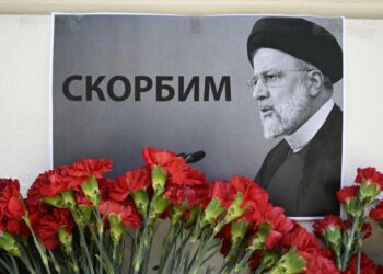 People bring flowers to the Iranian embassy to pay tribute to Iran's President Ebrahim Raisi and Foreign Minister Hossein Amir-Abdollahian, in Moscow on May 20, 2024. The placard with a Raisi portrait reads "(We) mourn". Russian President Vladimir Putin on May 20, 2024 hailed Iranian President Ebrahim Raisi as an "outstanding politician" and said his death in a helicopter crash was an "irreplaceable loss." Raisi was declared dead on on May 20, 2024 after rescue teams found his crashed helicopter in a fog-shrouded western mountain region of Iran. (Photo by Alexander NEMENOV / AFP)