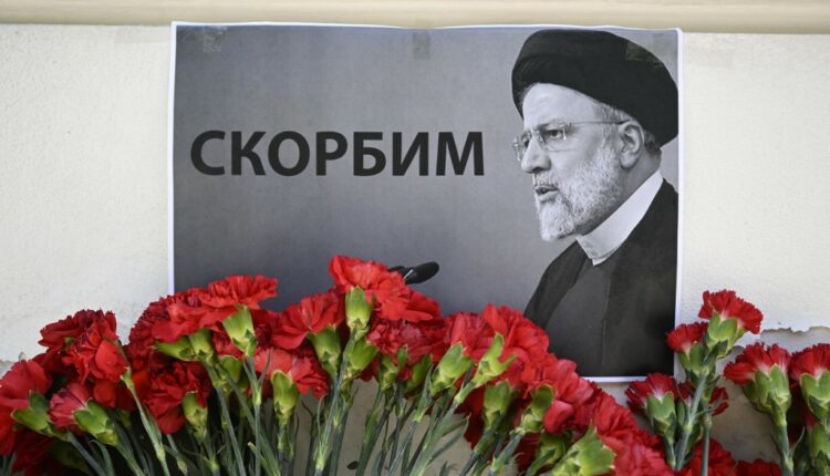 People bring flowers to the Iranian embassy to pay tribute to Iran's President Ebrahim Raisi and Foreign Minister Hossein Amir-Abdollahian, in Moscow on May 20, 2024. The placard with a Raisi portrait reads "(We) mourn". Russian President Vladimir Putin on May 20, 2024 hailed Iranian President Ebrahim Raisi as an "outstanding politician" and said his death in a helicopter crash was an "irreplaceable loss." Raisi was declared dead on on May 20, 2024 after rescue teams found his crashed helicopter in a fog-shrouded western mountain region of Iran. (Photo by Alexander NEMENOV / AFP)