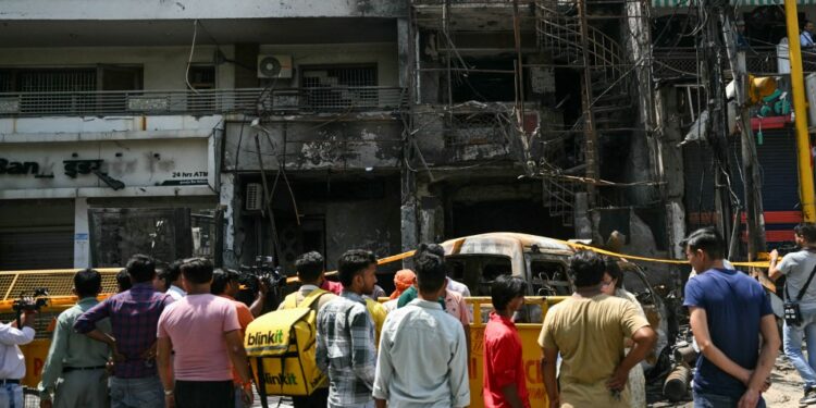 Men gather near the remains of an accident site a day after fire blazed through a children's hospital in New Delhi on May 26, 2024. Six newborn babies have died after a fire tore through a children's hospital in the Indian capital, with people charging into the flames to rescue the infants, police said on May 26. (Photo by Arun SANKAR / AFP)