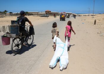 Palestinian children use a hazmat suit to transport belongings as they flee the area of Tel al-Sultan in Rafah in the southern Gaza Strip on May 30, 2024, amid the ongoing conflict between Israel and the militant group Hamas. (Photo by Eyad BABA / AFP)