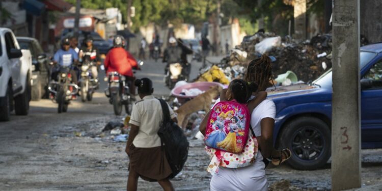 A woman walks carries child to school in a street of the Canape Vert neighborhood of Port Au Prince, June 18, 2024. Haiti welcomed a new government last week, completing the final step in a new political transition that many are hoping will bring a reprieve to the countrys ongoing gang-fueled crisis and pave the way for long-overdue general elections. (Photo by ROBERTO SCHMIDT / AFP)