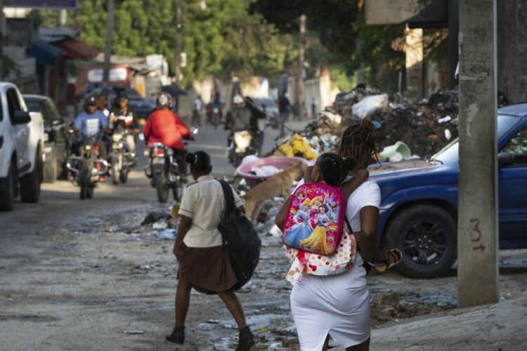 A woman walks carries child to school in a street of the Canape Vert neighborhood of Port Au Prince, June 18, 2024. Haiti welcomed a new government last week, completing the final step in a new political transition that many are hoping will bring a reprieve to the countrys ongoing gang-fueled crisis and pave the way for long-overdue general elections. (Photo by ROBERTO SCHMIDT / AFP)