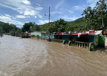 La gente se encuentra afuera de sus casas inundadas después de que un río creciera debido a las fuertes lluvias. Foto AFP.